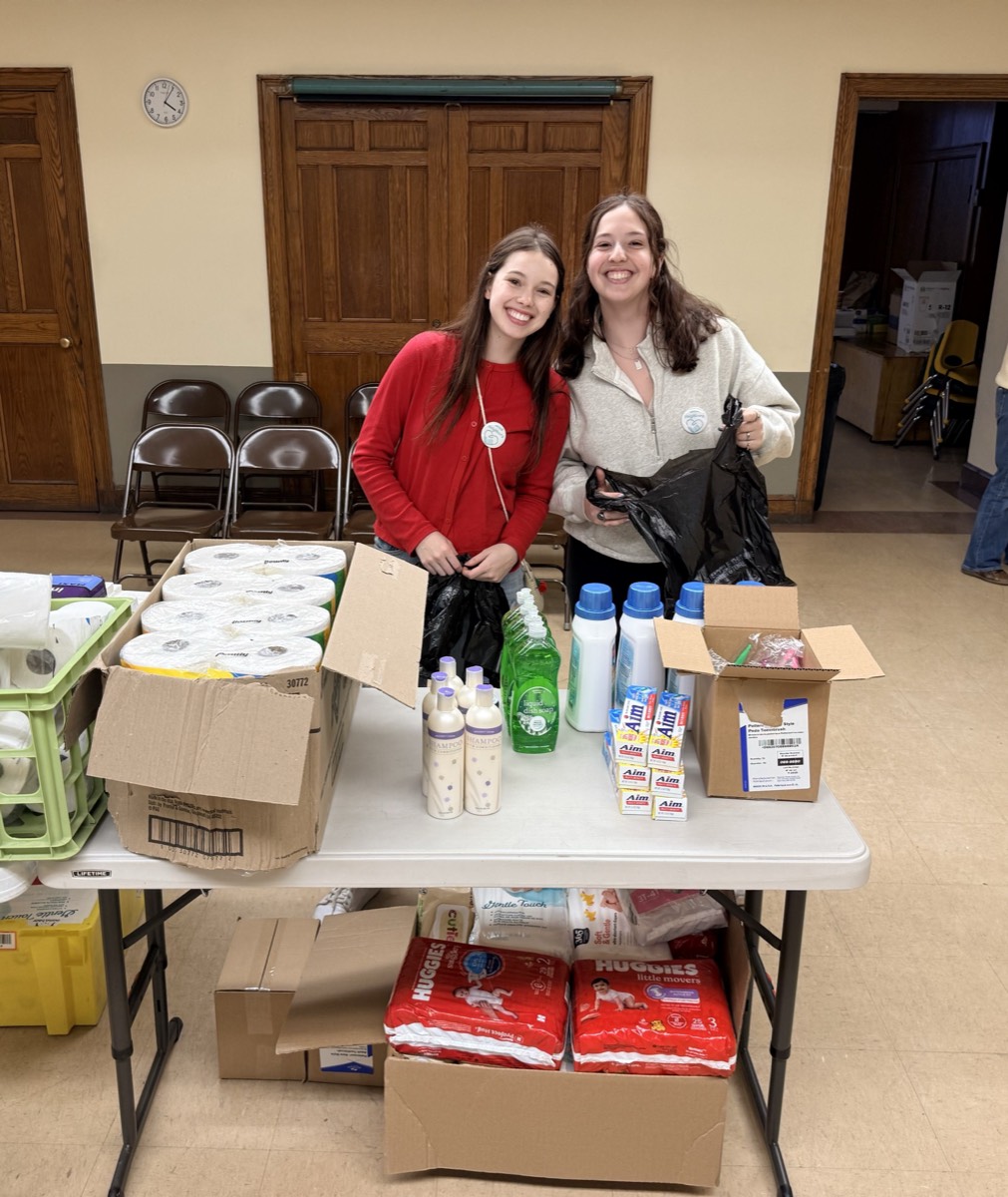 Volunteers at a table of hygiene essentials, diapers, and household supplies for neighbors